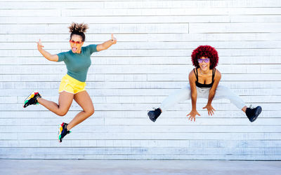 Full length of woman jumping against wall