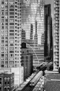 An  train is traveling between skyscrapers in the city.