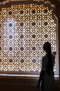 Full length of woman standing against window