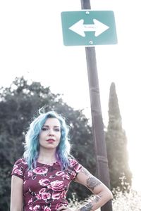 Portrait of young woman standing against sky