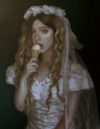 Portrait of female model in costume having ice cream cone against black background