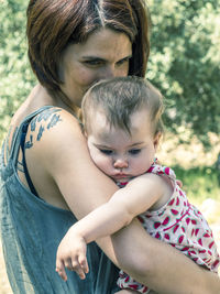 Close-up of mother carrying toddler daughter at park