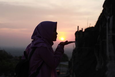 Side view of man standing against sky during sunset