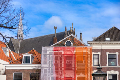 Orange scaffolding with protective net against historic building   in leiden, netherlands