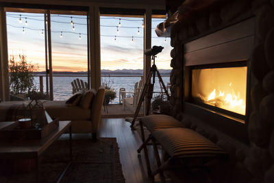 Sunset with burning fireplace at beach house.