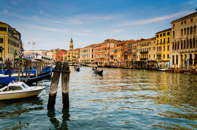 Boats moored on canal against buildings in city