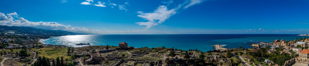 Panoramic view of jbeil district by sea against blue sky