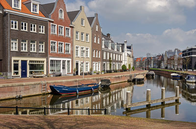 Boats in canal in city against sky