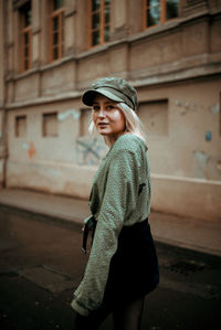 Side view of young woman standing against building in city