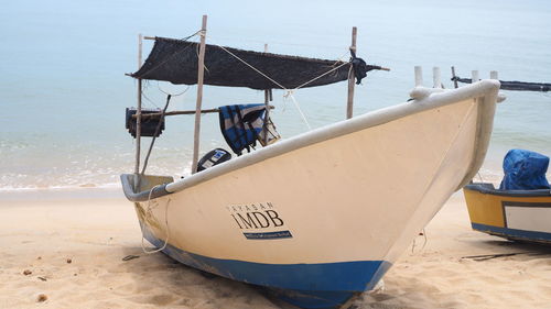 Boat moored on beach against sky