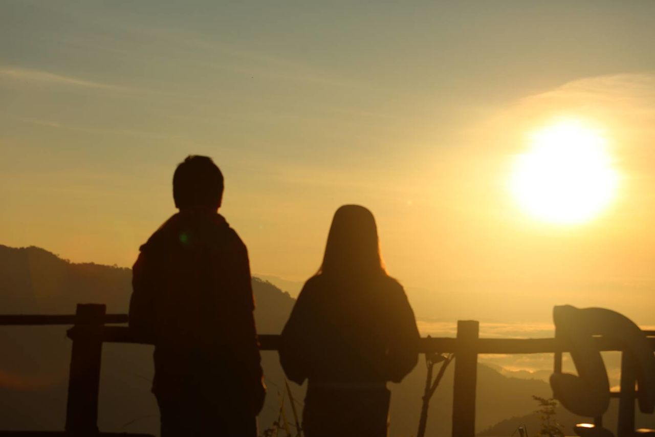 sunset, silhouette, real people, two people, men, railing, leisure activity, standing, orange color, nature, sky, outdoors, rear view, women, lifestyles, beauty in nature, sun, togetherness, scenics, sea, water, weekend activities, vacations, sunlight, childhood, sitting, friendship, boys, bonding, day, adult, people