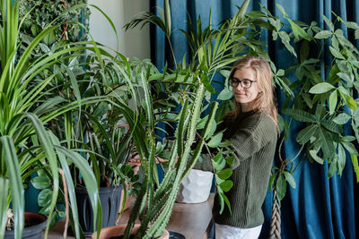 Young woman in green sweater taking care of the plants at home