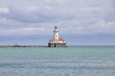 Lighthouse by sea against sky