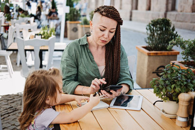 Freelance parents. busy working mom with cell phone and tablet working in street cafe with baby