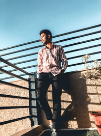 Full length of young man standing against railing