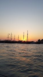 Silhouette sailboats in sea against clear sky during sunset