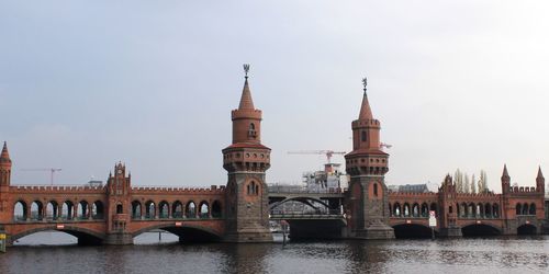 Bridge over river by buildings against sky in city