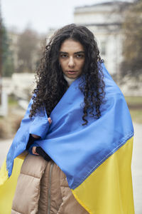Portrait of young woman wrapped in ukrainian flag