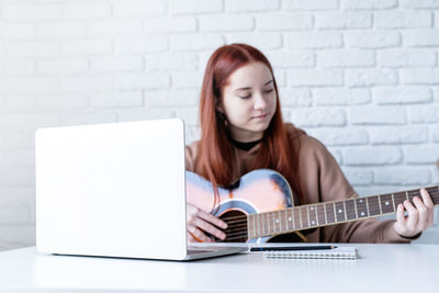 Young woman using laptop while sitting on sofa at home