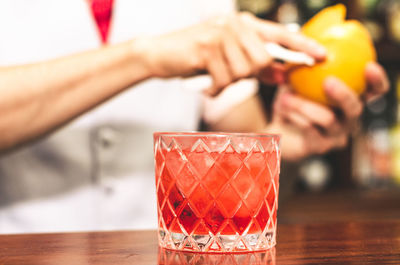 Close-up of hand holding drink on table