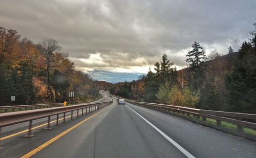 Road passing through mountain against cloudy sky