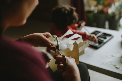 Midsection of woman cutting paper at home