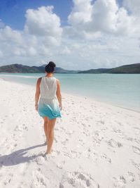 Rear view of woman at beach against sky