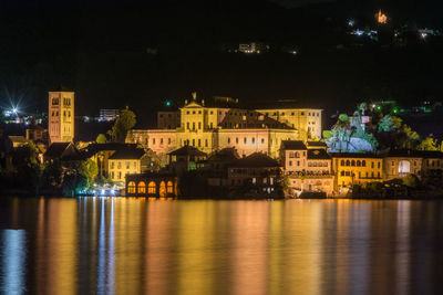 Illuminated buildings by river at night