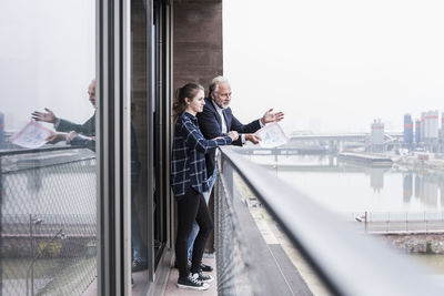 Mature businessman and young woman talking on balcony
