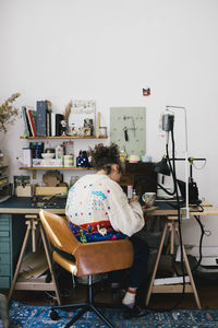 Female jewelry maker sitting on chair while working at home