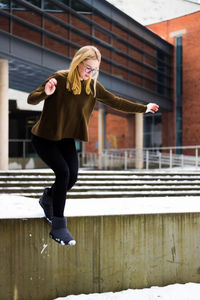 Full length of girl jumping on snow in city