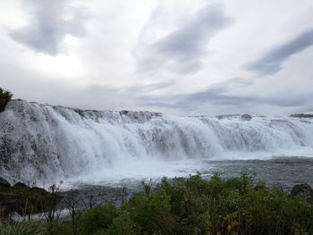 Scenic view of waterfall against sky