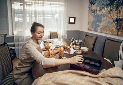 Young woman packs cupcakes in craft. delivery. chef bakes cakes in kitchen, copy space, mock up