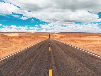 Road passing through land against sky