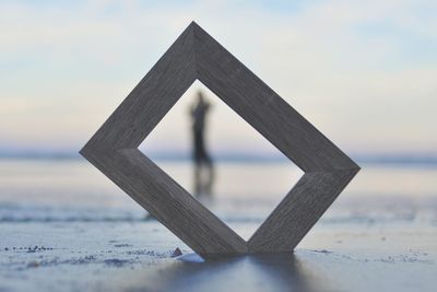 Close-up of wooden table by sea against sky