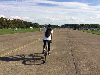 Rear view of man riding bicycle on road