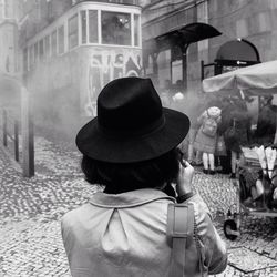 Rear view of woman with hat against cable car in city
