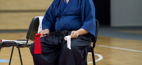 Midsection of karate referee holding flags while sitting on chair