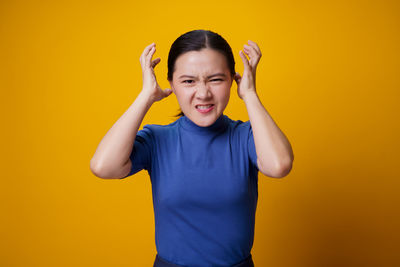 Happy boy standing against yellow background