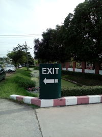 Information sign on road in city against sky