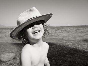 Portrait of boy wearing hat at beach against sky