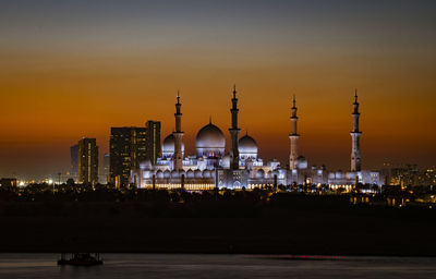 Illuminated buildings in city against sky during sunset