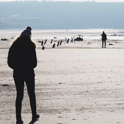 Rear view of silhouette woman standing on beach against clear sky