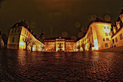 Illuminated buildings by street at night