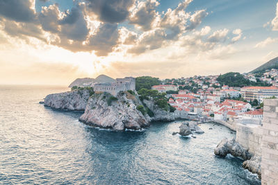 City by sea against sky during sunset