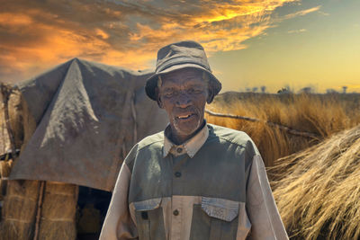 Portrait of man standing on field against sky during sunset