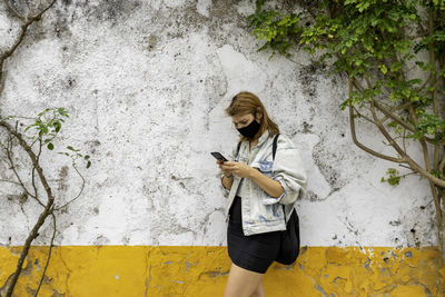 Full length of young woman standing against wall