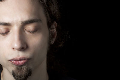 Close-up of man with eyes closed over black background