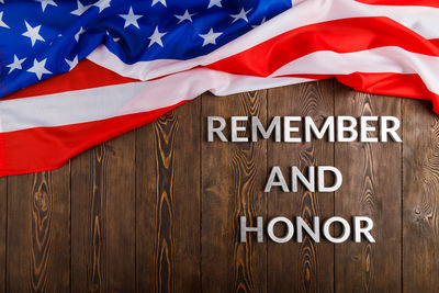 Words remember and honor laid with silver metal letters on wooden background with usa flag above