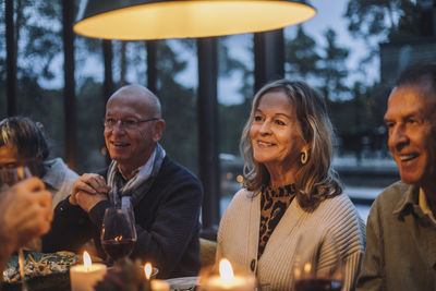 Smiling senior woman with male retired friends during dinner party